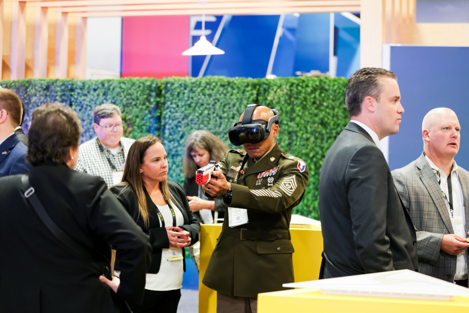 A sergeant major in a VR headset aiming a training device as others watch