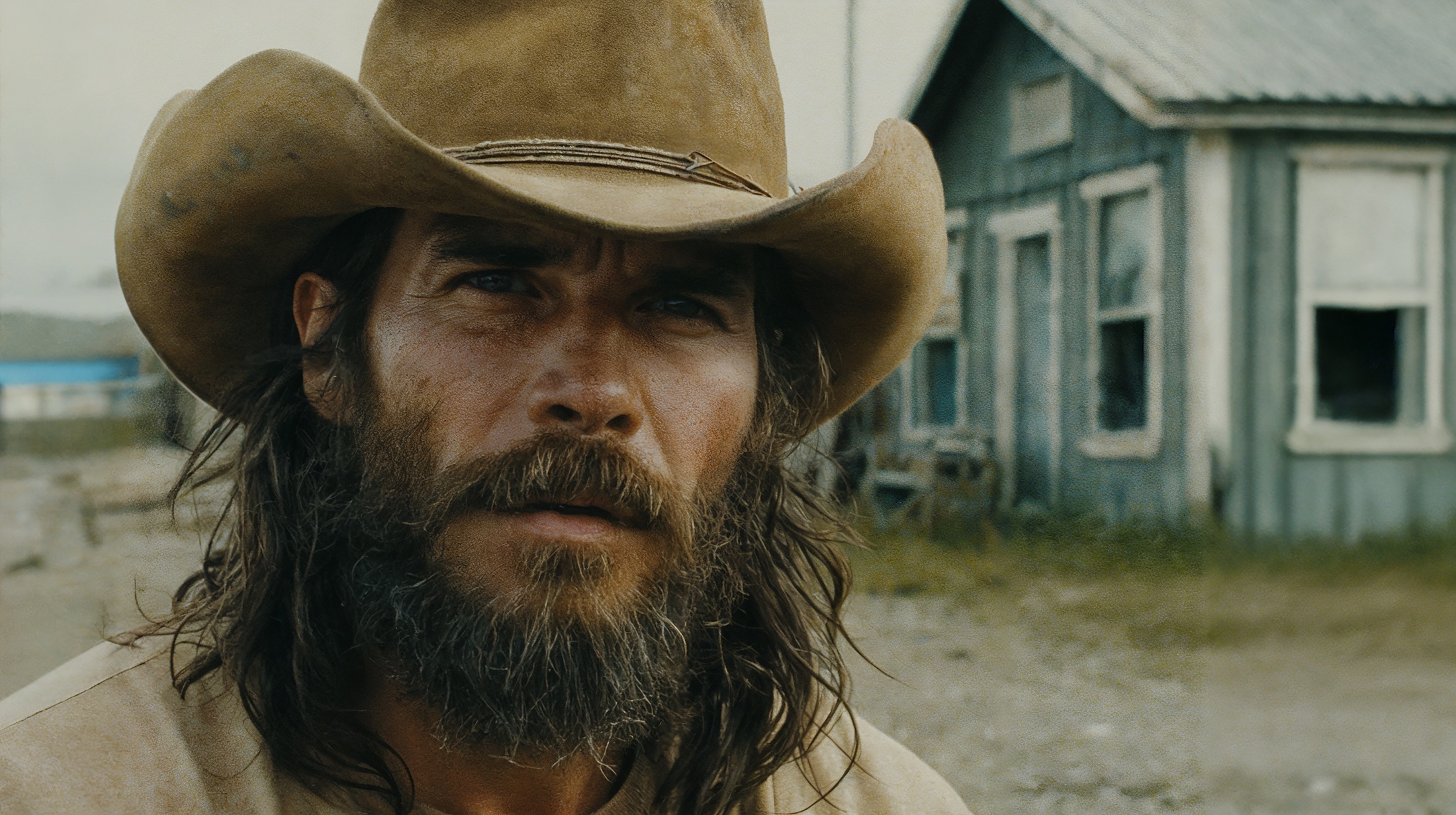 Wyatt Peoples in a cowboy hat, a wooden house behind him