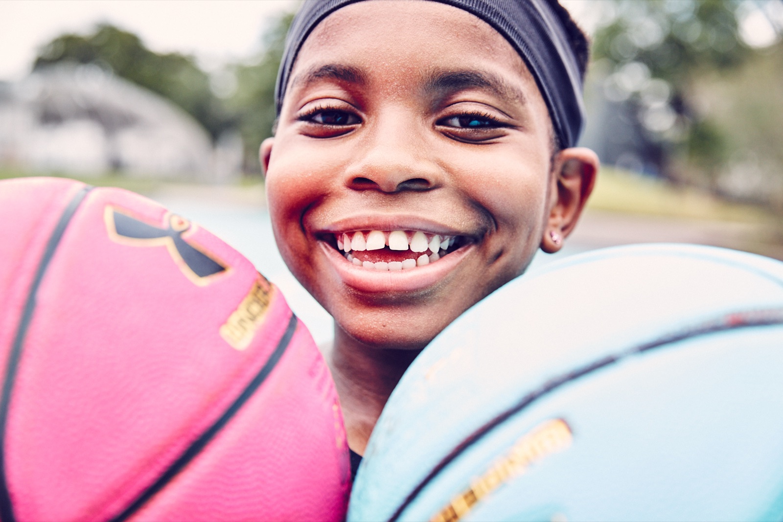 Zaila Avant-garde smiling between two basketballs